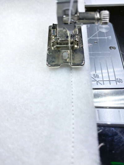 close up of sewing machine foot on machine sewing interfacing