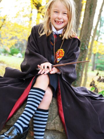 girl in costume sitting on stone wall outdoors