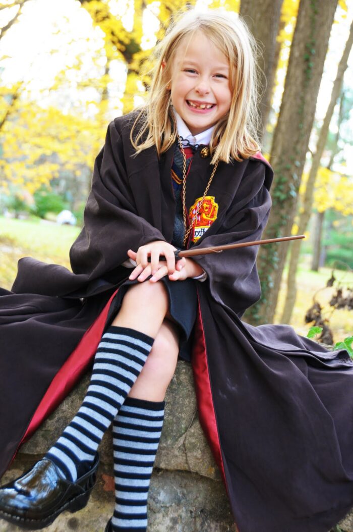 girl in costume sitting on stone wall outdoors