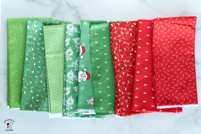 Christmas fabrics in reds and greens in stack on white marble tabletop