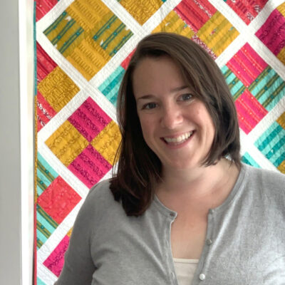 Photo of Amy Ball in front of colorful quilt