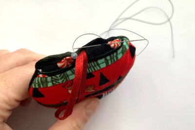 red, green and black christmas ornament in construction on white table