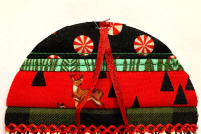 red, green and black christmas ornament in construction with batting on white table