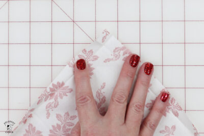 hand folding fabric on white cutting mat