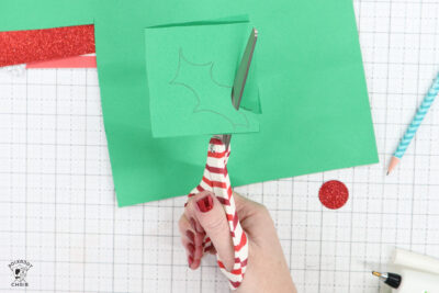 scissors cutting green paper on white cutting mat