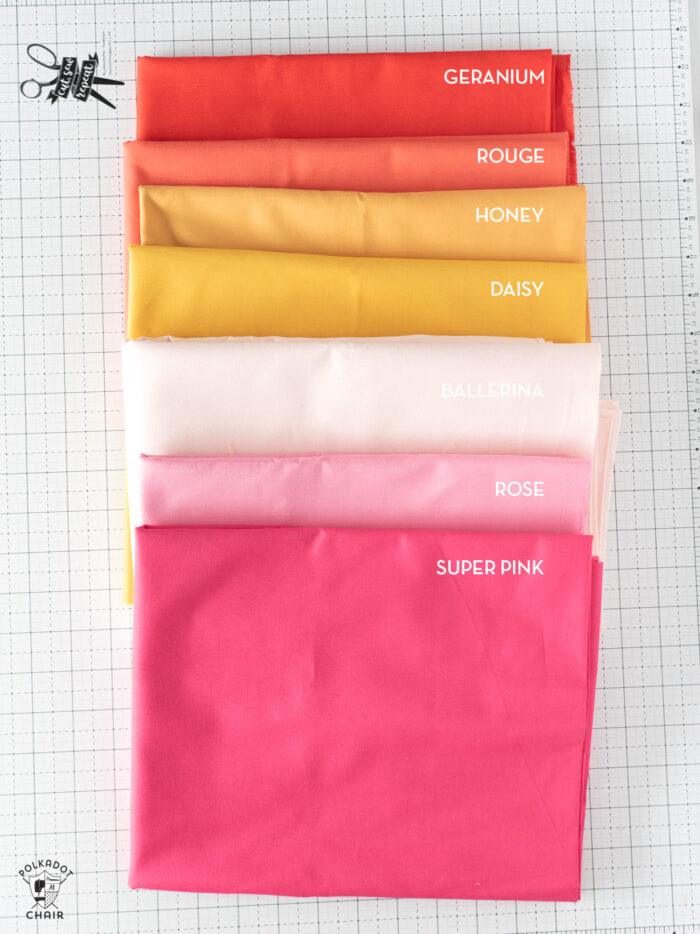 Pink and orange fabrics laid out on white cutting mat