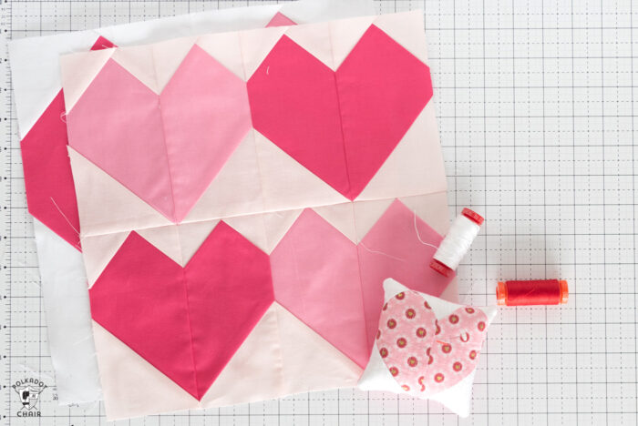 Pink and white heart quilt block on white cutting mat