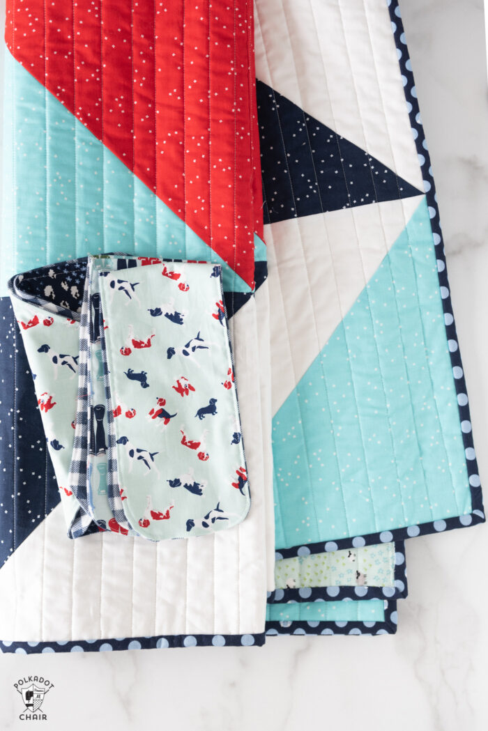 red white and blue baby quilt folded on white table