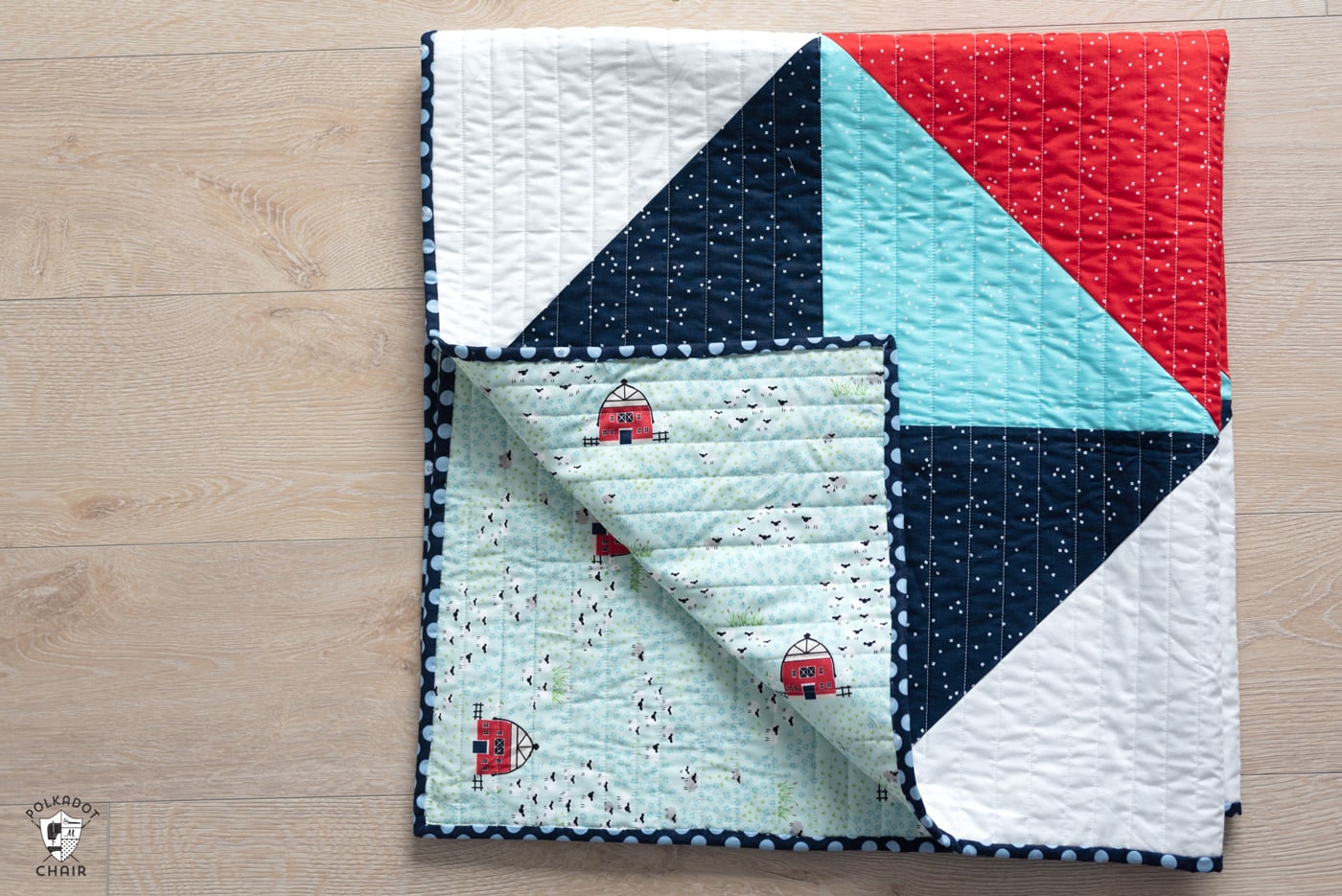 red white and blue baby quilt folded on wood floor