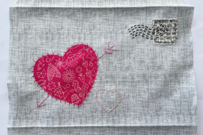 red heart and hand stitching on gray fabric