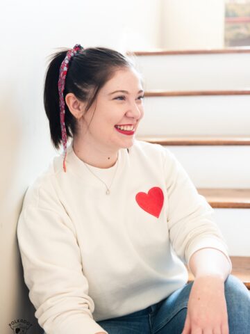 girl wearing cream sweatshirt with red heart