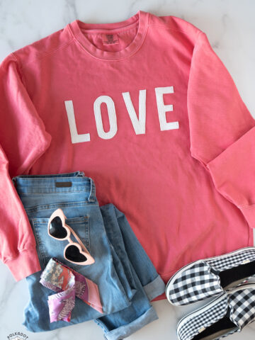 coral love sweatshirt, jeans and shoes on white table