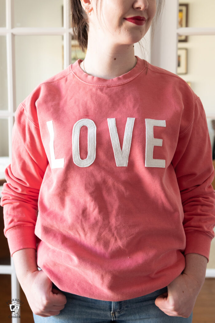 girl in coral sweatshirt standing in front of french doors