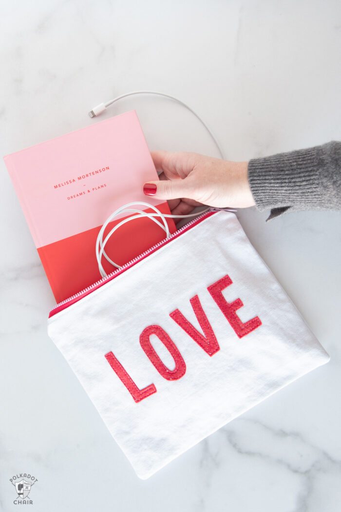 white canvas zip pouches with red lettering and hearts on white tabletop