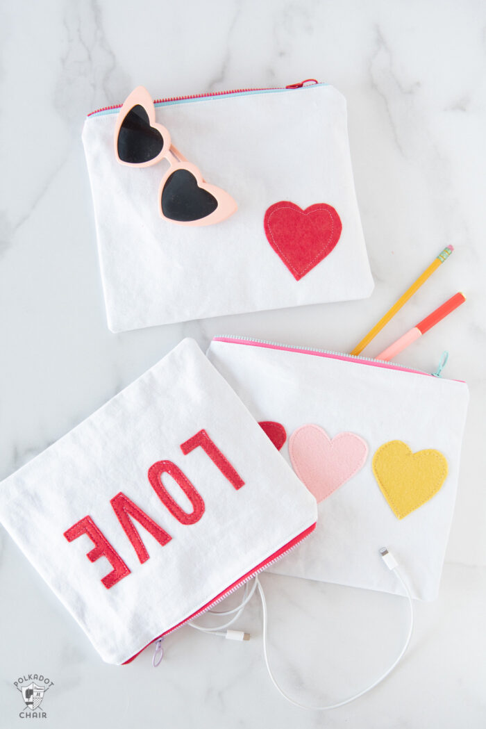 white canvas zip pouches with red lettering and hearts on white tabletop