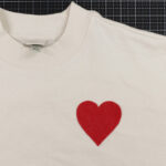 red heart on ivory shirt on black cutting mat
