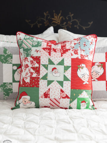 red, green and white patchwork christmas pillows on white bed