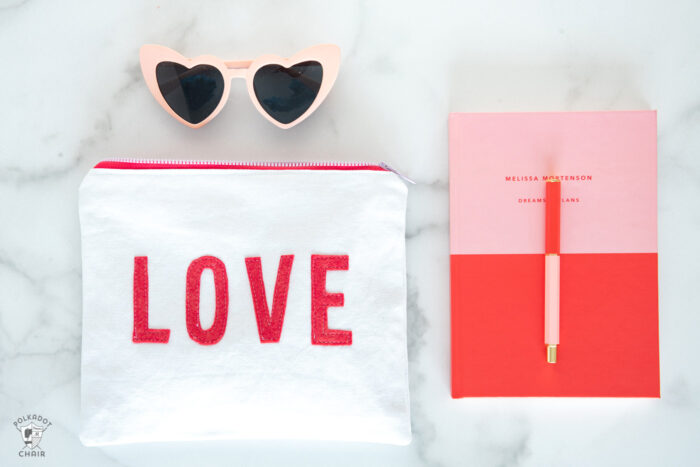 white canvas zip pouches with red lettering and hearts on white tabletop