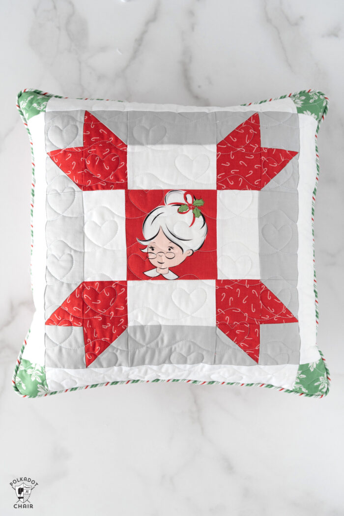 red, green and white patchwork christmas pillows on white tabletop