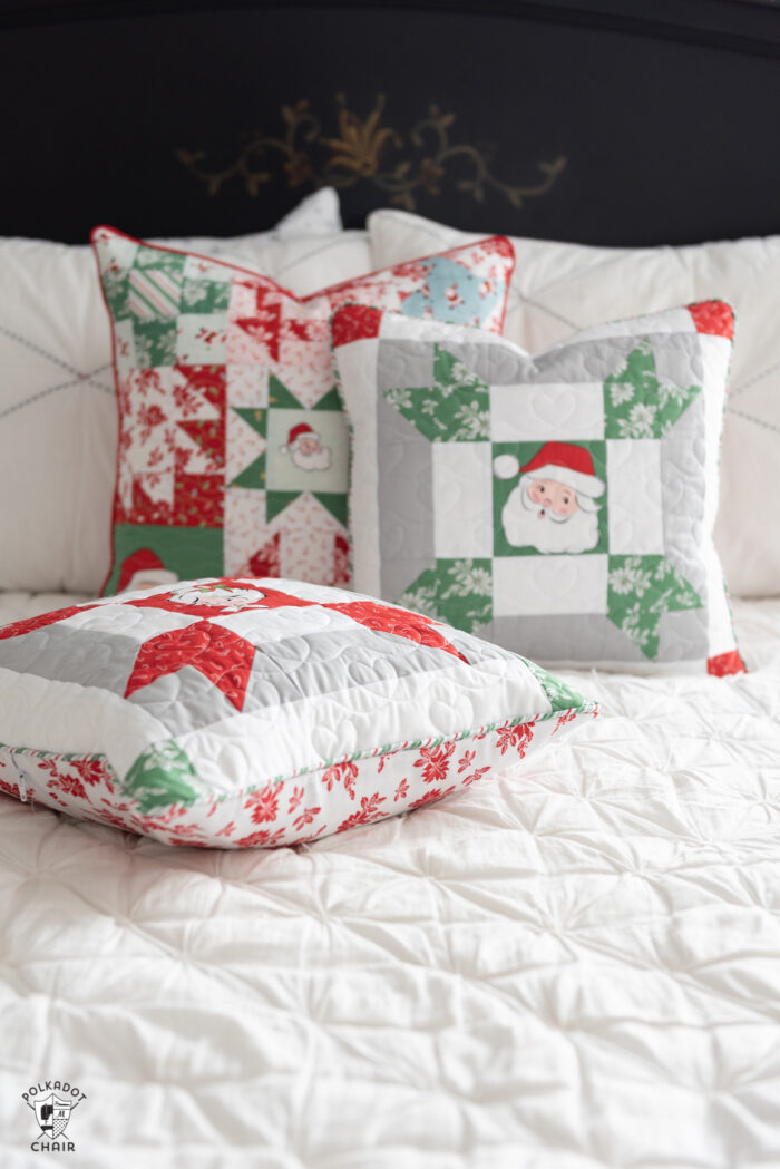red, green and white patchwork christmas pillows on white bed