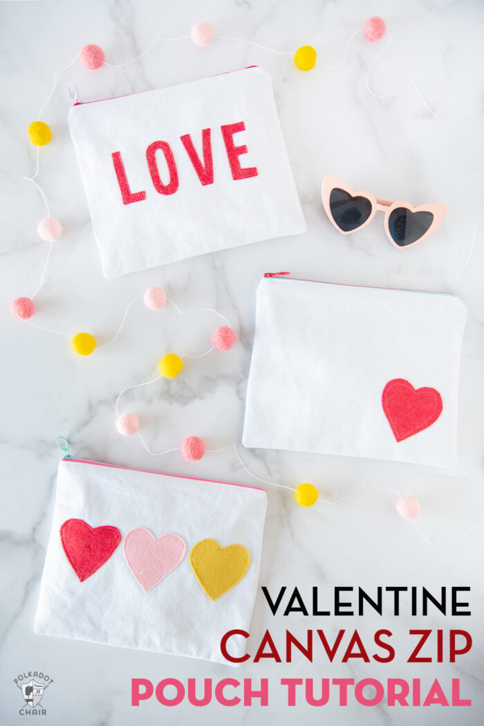 white canvas zip pouches with red lettering and hearts on white tabletop