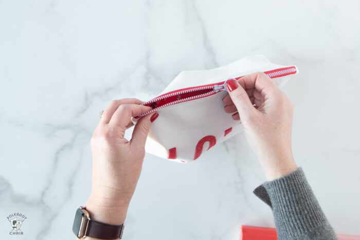 white canvas zip pouches with red lettering and hearts on white tabletop