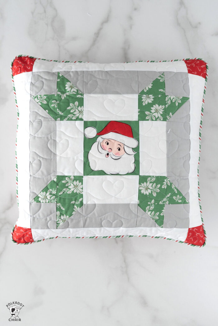 red, green and white patchwork christmas pillows on white tabletop
