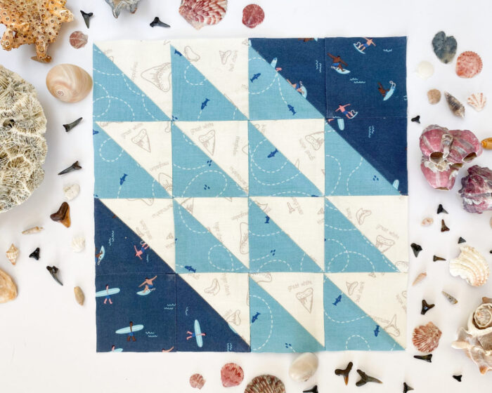 blue quilt block on white table with seashells around the perimeter