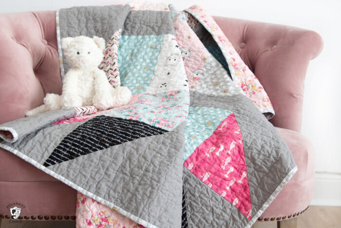 pink white and gray baby quilt on pink chair