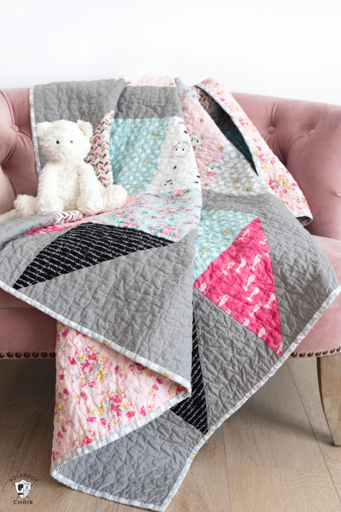 pink white and gray baby quilt on pink chair