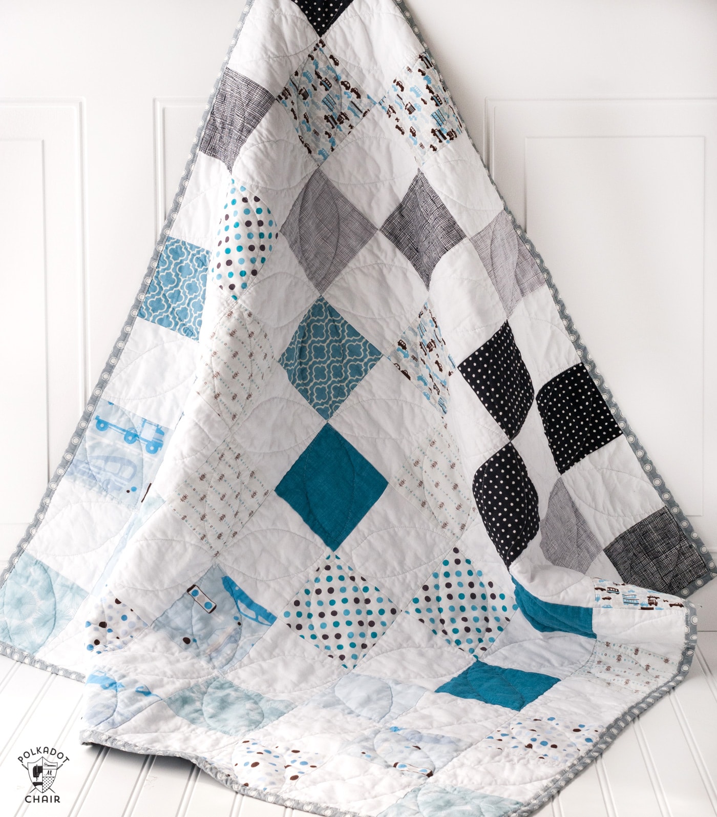 blue white and gray baby quilt on door