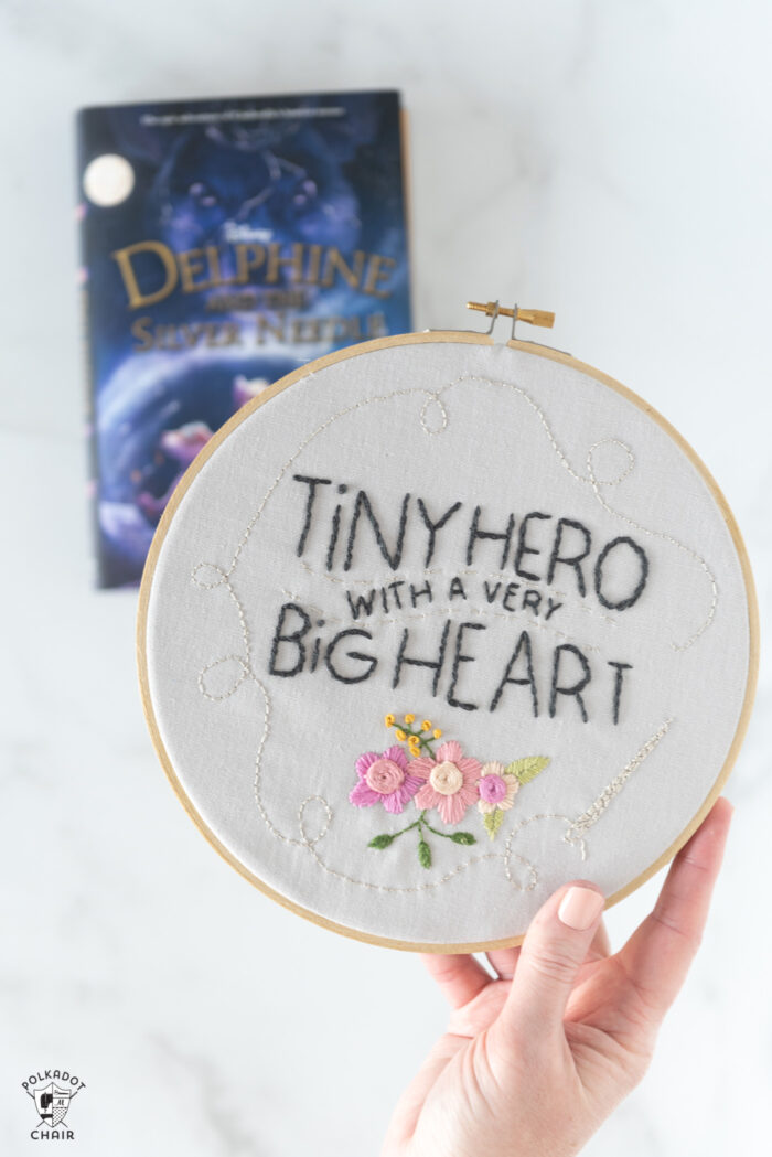 hand holding embroidery hoop with text