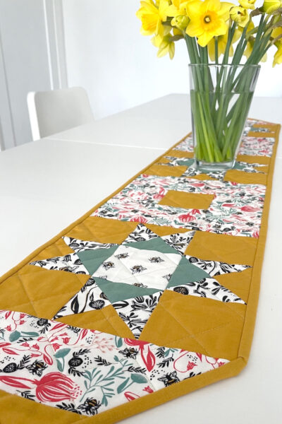 yellow, and green floral table runner on white table with flowers