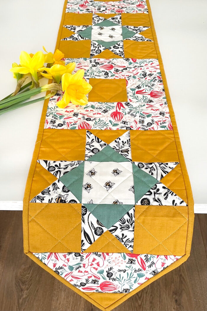 yellow, and green floral table runner on white table with flowers