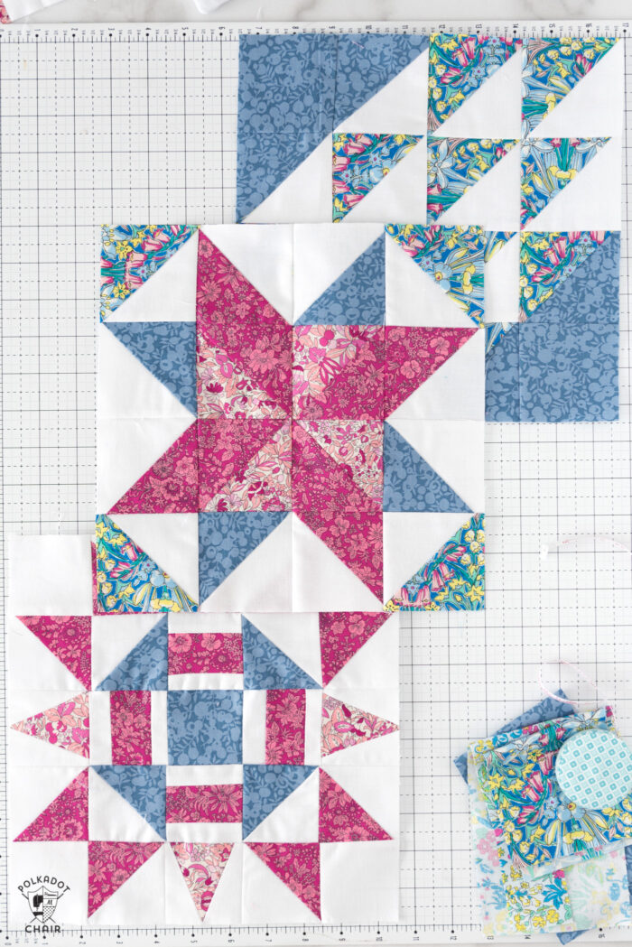 multiple red pink and white quilt blocks on white cutting mat