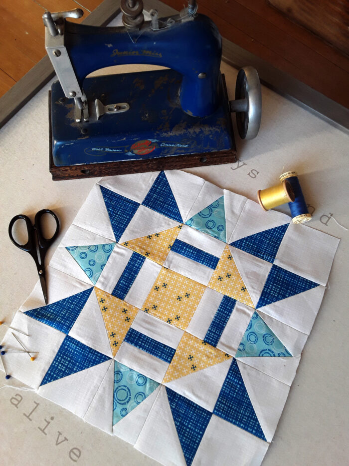 blue and yellow quilt block on white cutting mat