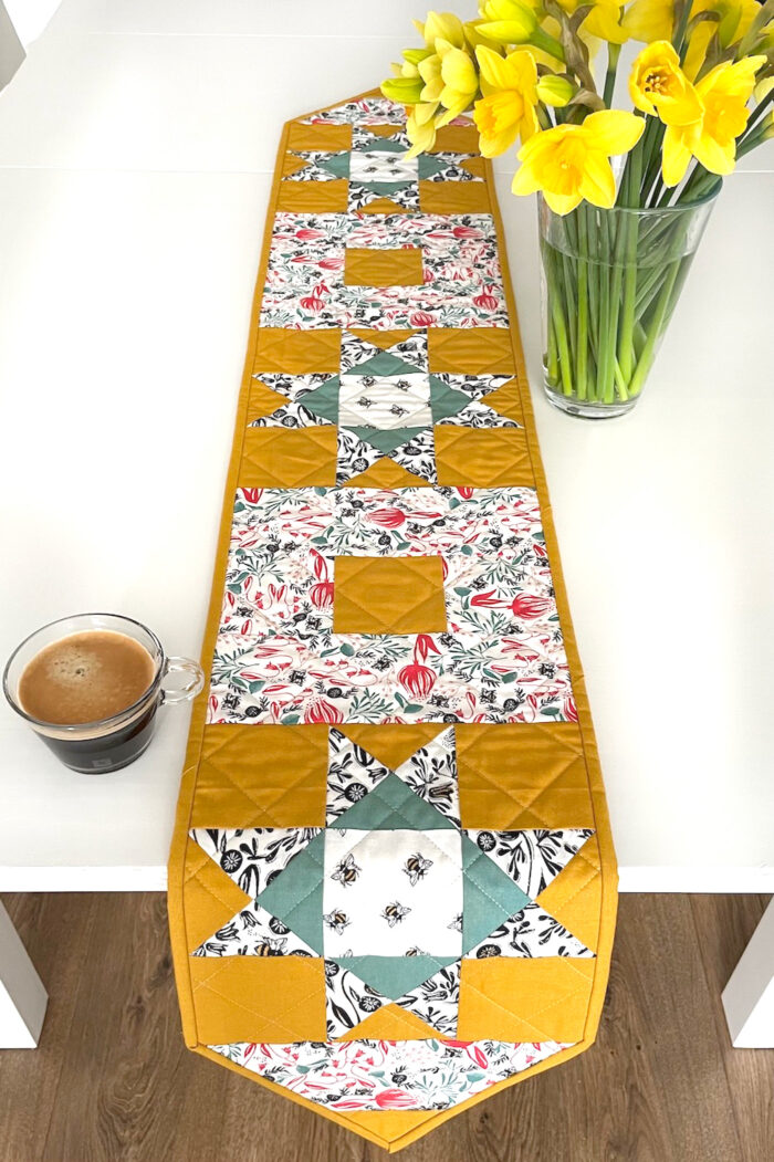 yellow, and green floral table runner on white table with flowers