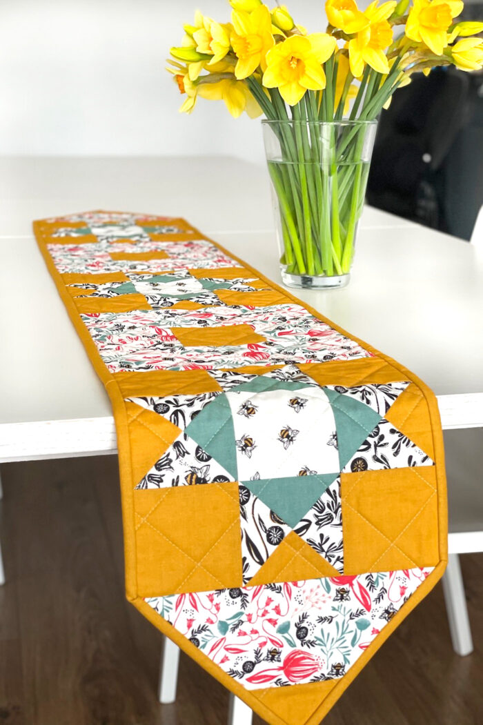 yellow, and green floral table runner on white table with flowers