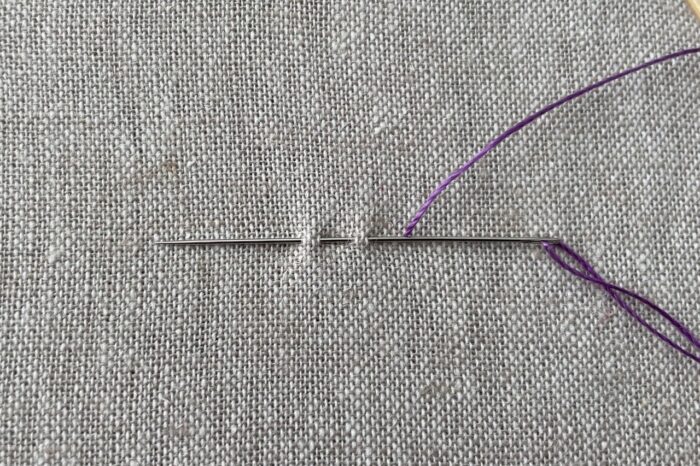 purple embroidery thread on needle on canvas
