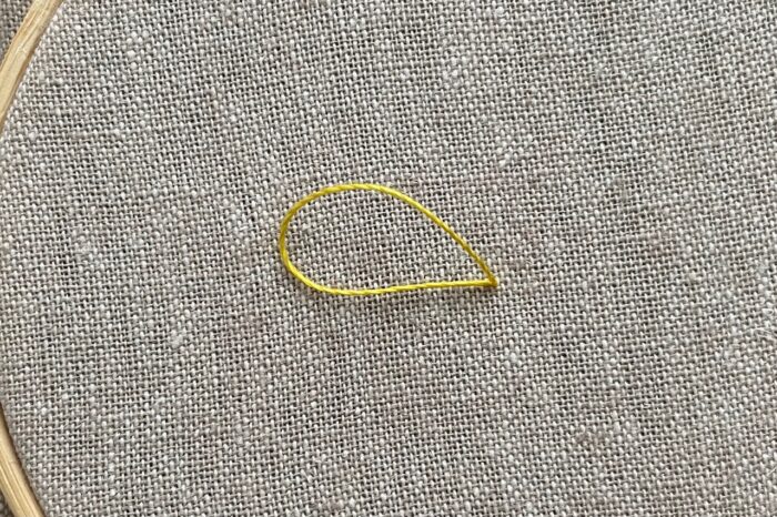 yellow embroidery thread on needle on canvas