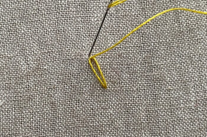 yellow embroidery thread on needle on canvas