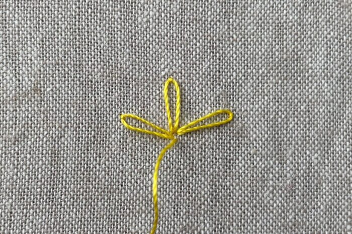 yellow embroidery thread on needle on canvas