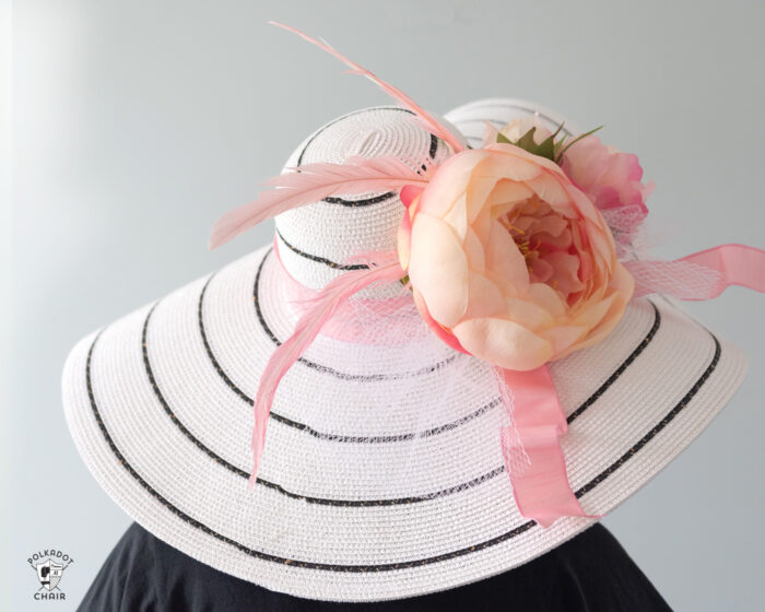 girl in white derby hat with pink flowers wearing a navy dress