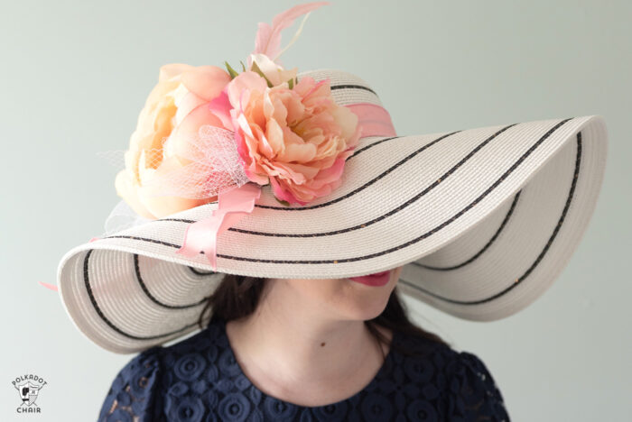 girl in white derby hat with pink flowers wearing a navy dress