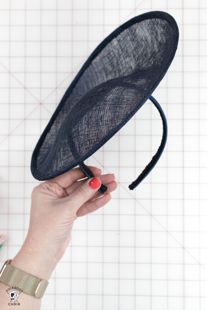 navy fascinator being held over white cutting mat