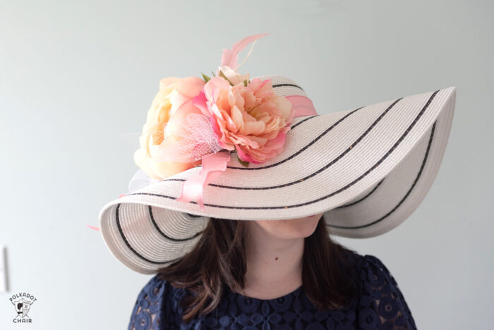 girl in white derby hat with pink flowers wearing a navy dress