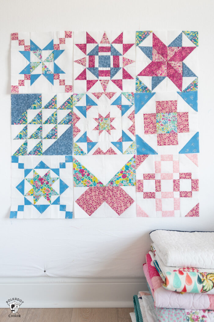 pink, blue and white sampler quilt blocks hanging on a design wall