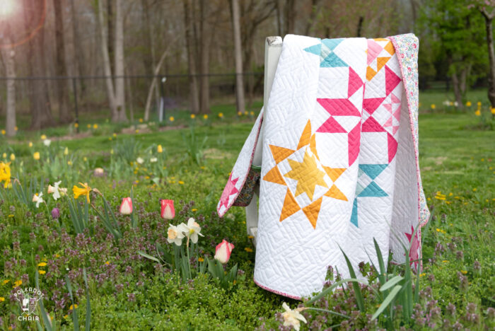 pink, blue and yellow geometric quilt in field of flowers