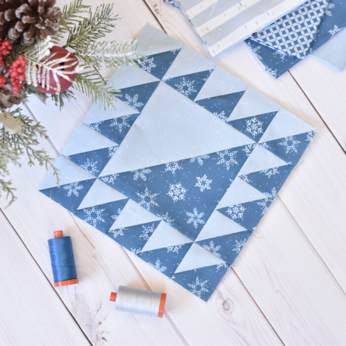 navy and white quilt block on cutting mat with quilting supplies