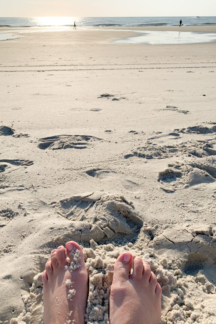 feet on beach with water in the distance